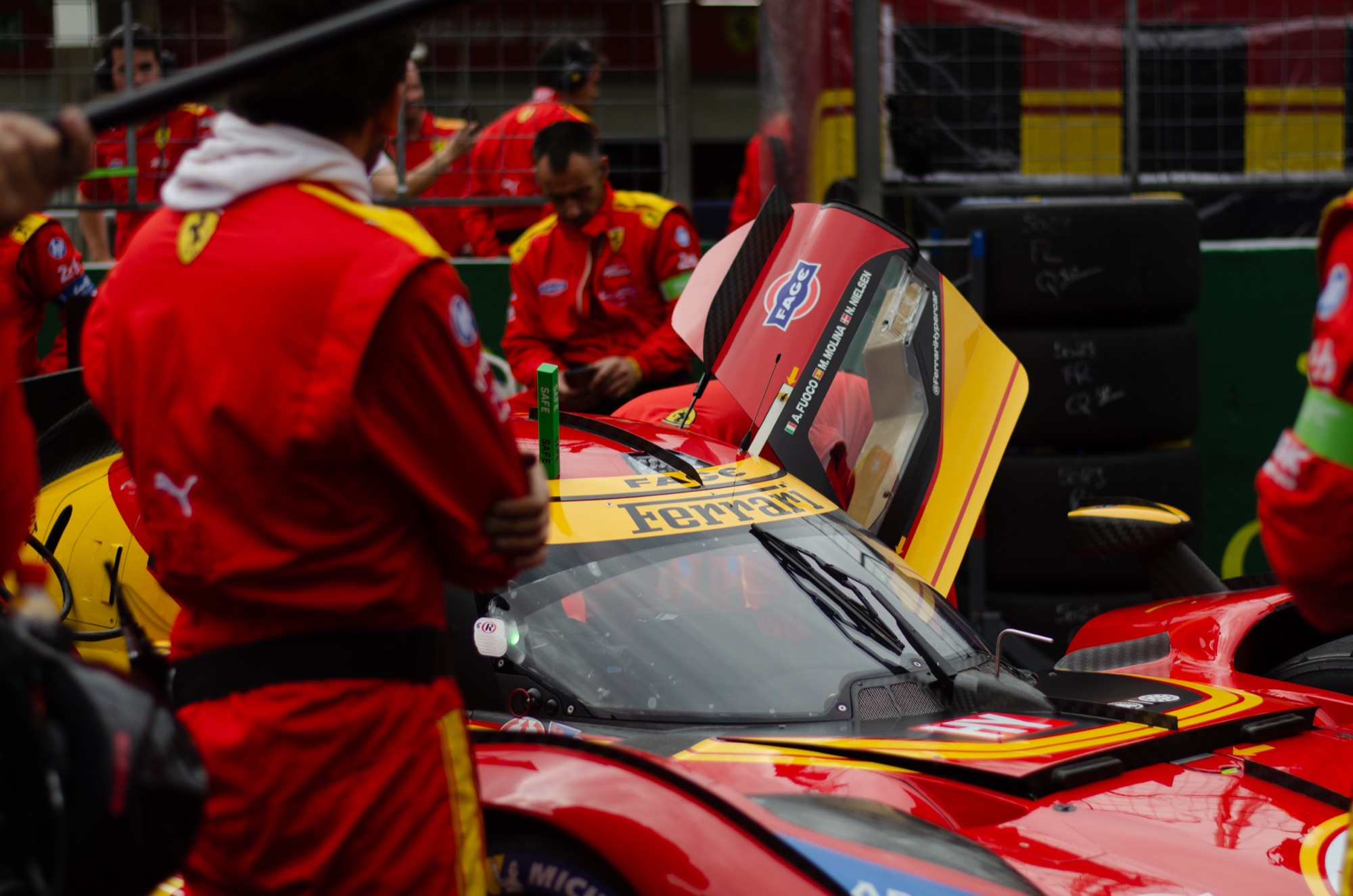 Ferrari 499P da AF Corse na grid, cercada pela equipe de macacão vermelho