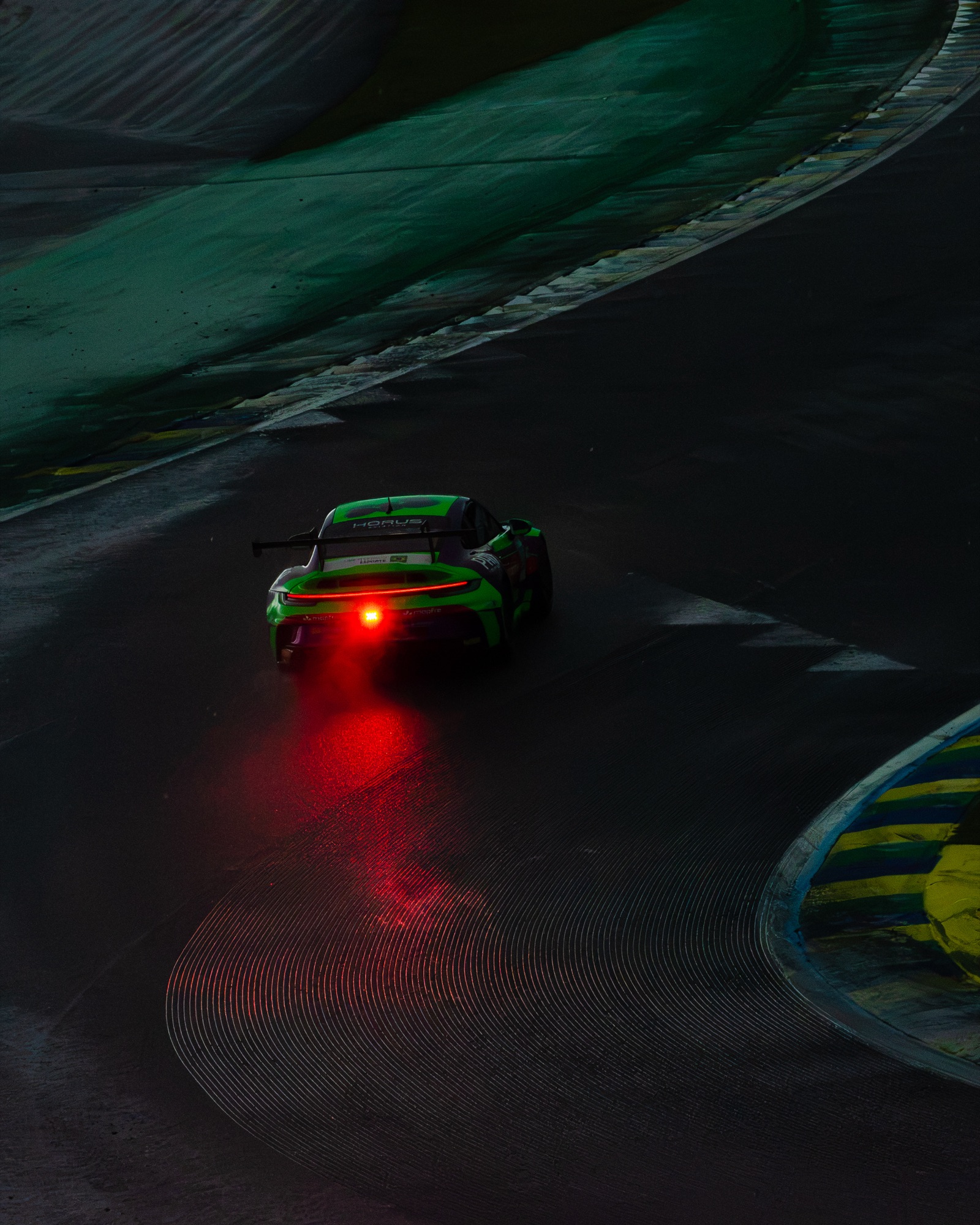 Porsche 911 GT3 Cup verde no escuro, a luz de chuva vermelha refletida na pista molhada