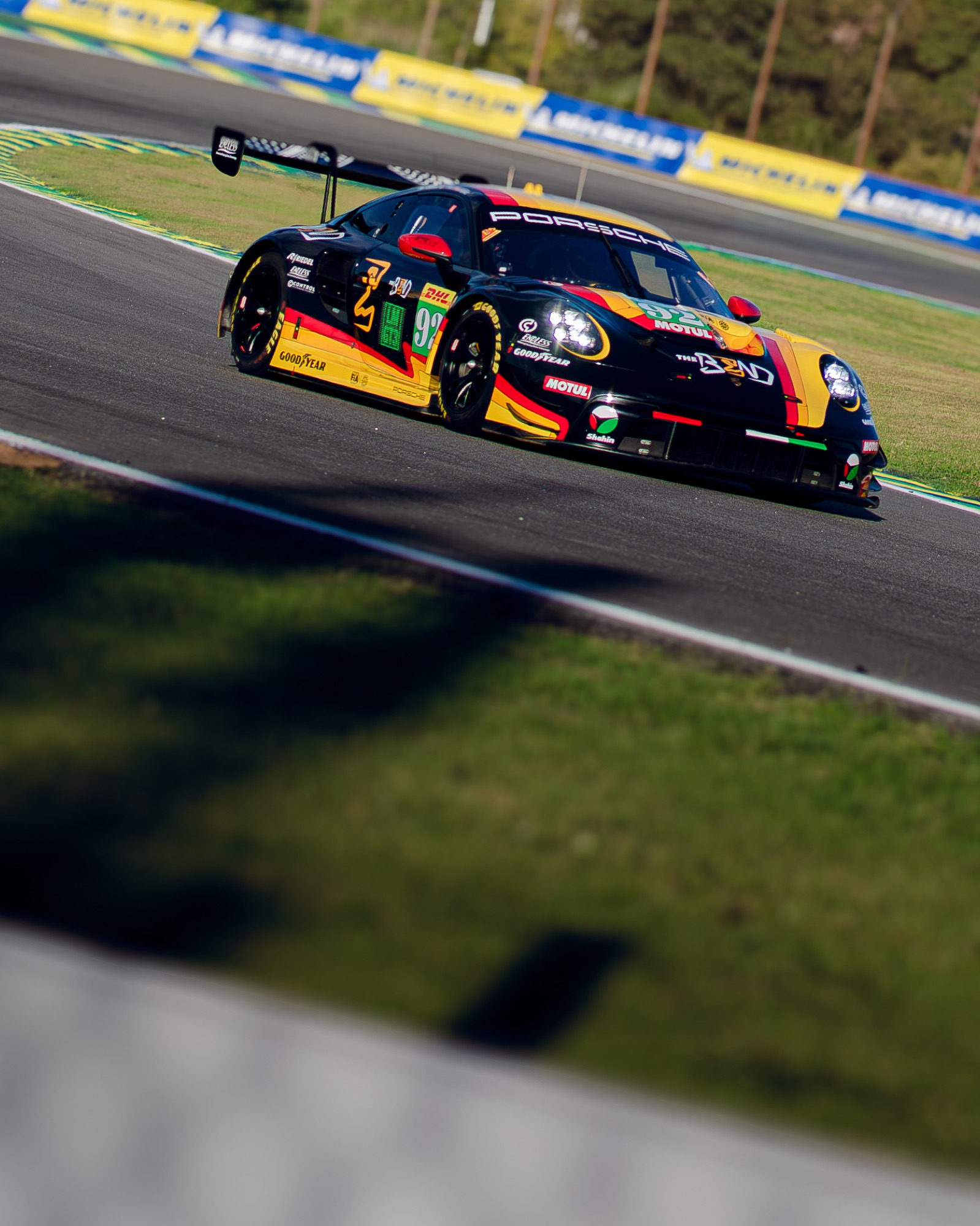 Porsche 911 GT3 R #92 da Manthey em velocidade, visto por cima de um primeiro plano desfocado