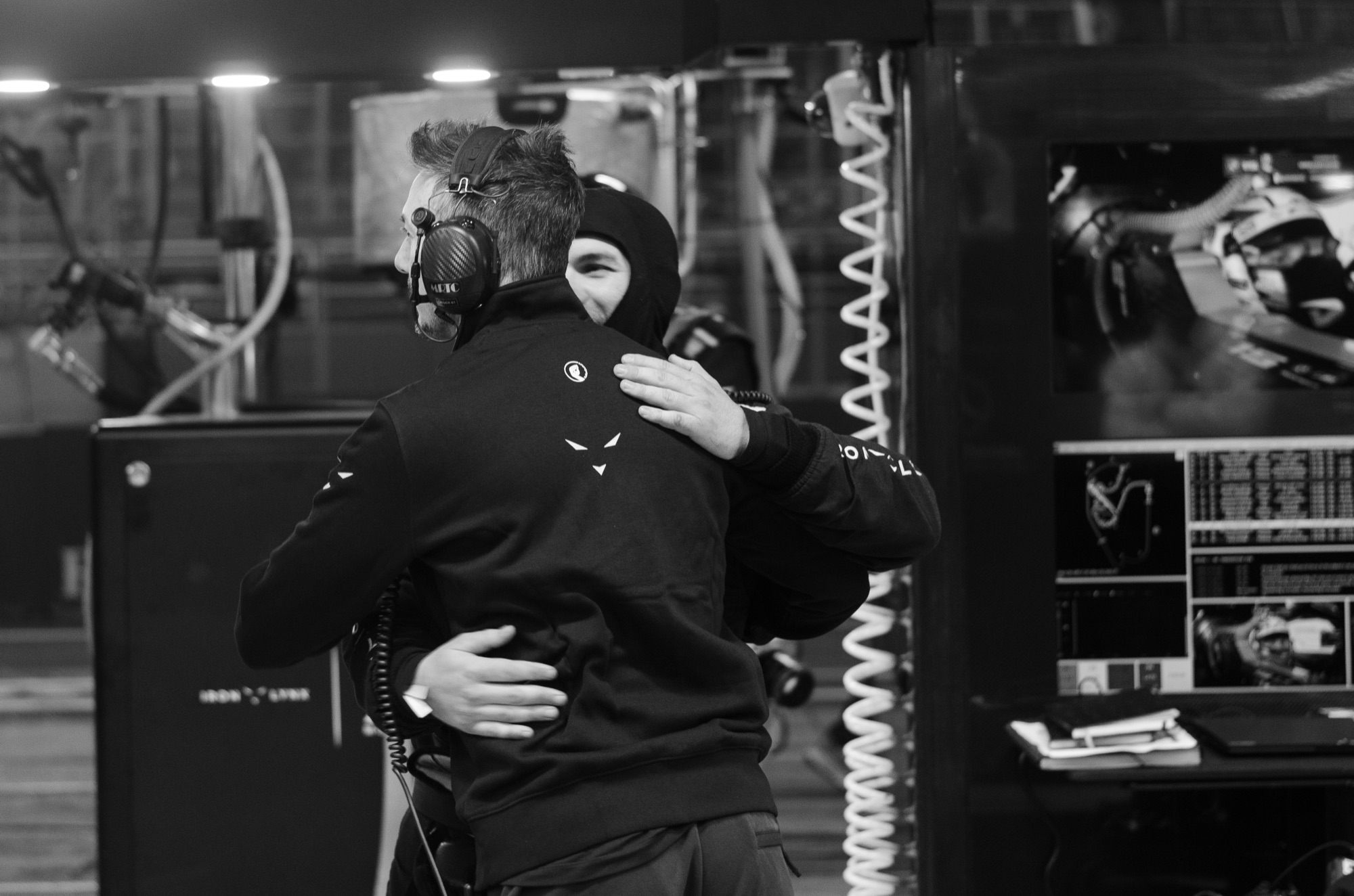 Abraço entre piloto e engenheiro no box da Iron Lynx, em preto e branco